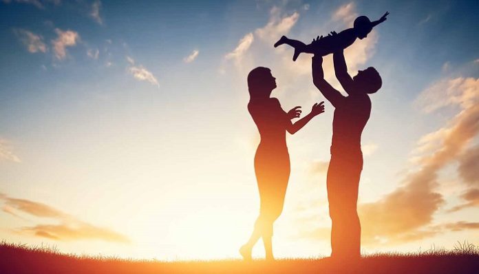 Happy family together, parents with their little child at sunset.